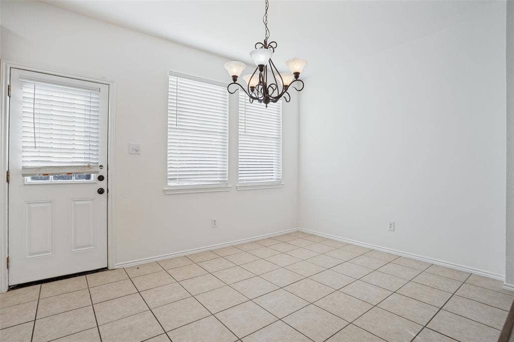 1507 Bankston Drive, Wylie, TX 75098 Room featuring neutral tile flooring, dual windows with horizontal blinds, a decorative multi-arm chandelier, and a white exterior-access door with an integrated window