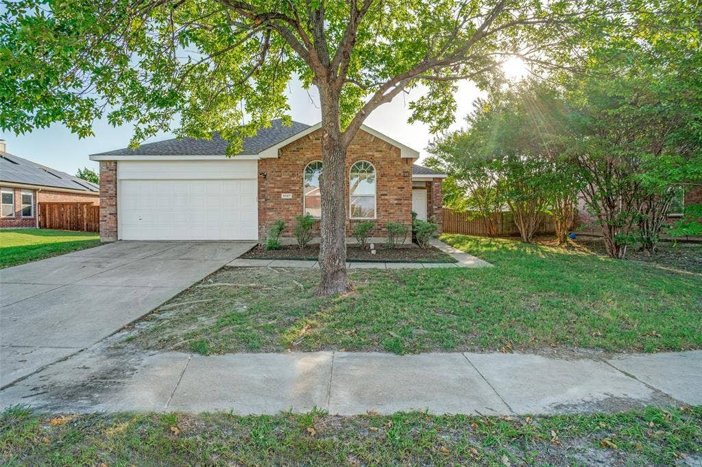 1507 Bankston Drive, Wylie, TX 75098 Brick exterior featuring a gabled roof, two-car garage, arched windows, and mature landscaping