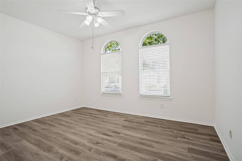 1507 Bankston Drive, Wylie, TX 75098 Room featuring wood-finish flooring, two arched windows with installed blinds, and a ceiling fan with integrated lighting