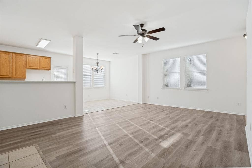 1507 Bankston Drive, Wylie, TX 75098 Open-concept interior featuring wood-finish flooring, a ceiling fan with integrated lighting, wood cabinetry, and multiple windows