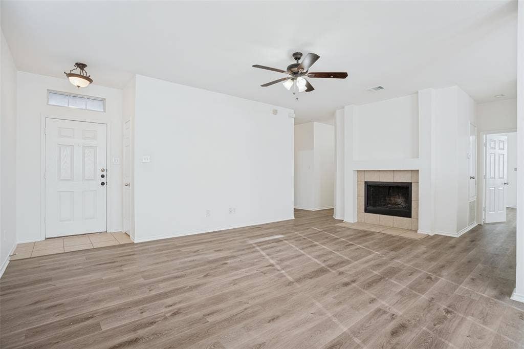 1507 Bankston Drive, Wylie, TX 75098 Living area featuring wood-finish flooring, a fireplace with tile surround, a ceiling fan with integrated lighting, and a front entry door with a transom window