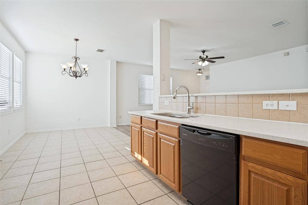 1507 Bankston Drive, Wylie, TX 75098 Kitchen featuring natural wood cabinetry, solid surface countertops, a ceramic tile backsplash, an undermount stainless steel sink with a goose-neck faucet, and a black dishwasher