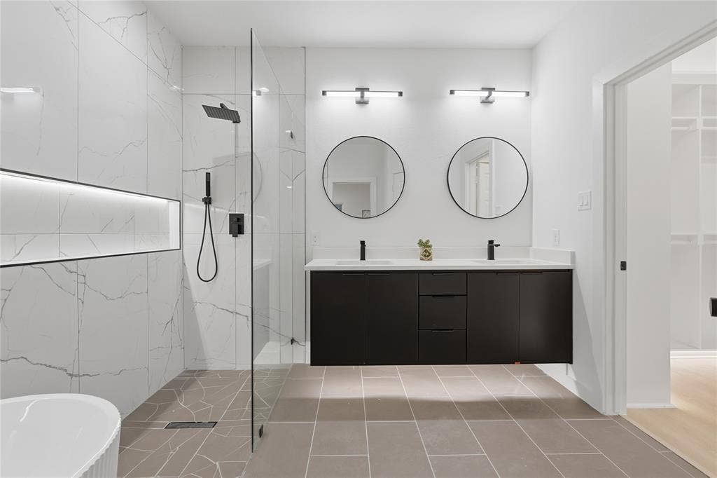 Floating dark-toned dual vanity with rectangular undermount sinks and matte black fixtures, paired with circular wall-mounted mirrors and linear vanity lighting