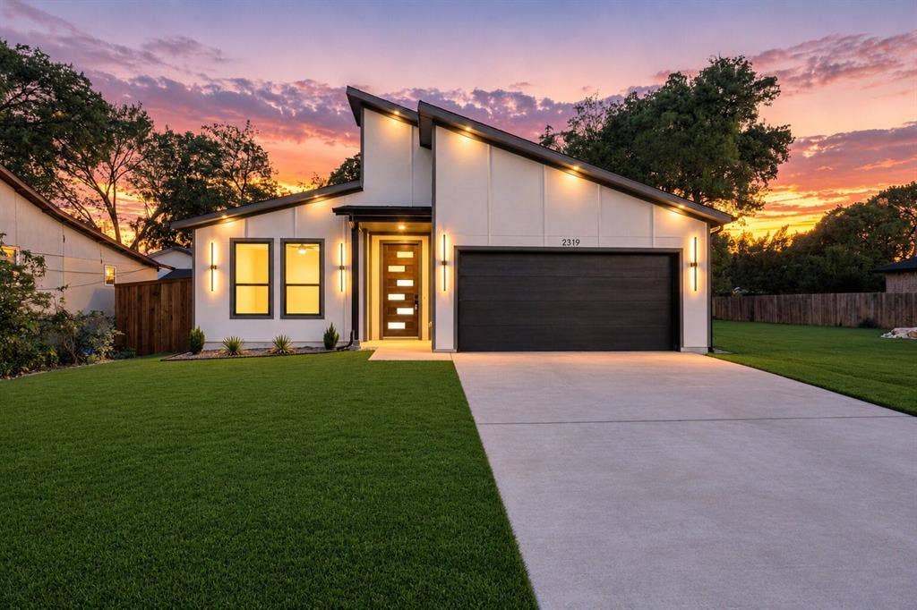 Contemporary exterior featuring board-and-batten siding, a prominent mono-pitch roofline, a multi-pane glass entry door, and a two-car garage