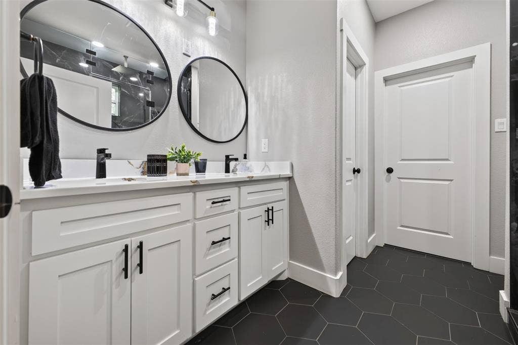 9116 Beckleycrest Avenue, Dallas, TX 75232 Primary Bathroom with double sink vanity with white cabinetry, plenty of storage, sleek black fixtures, and custom tile flooring.