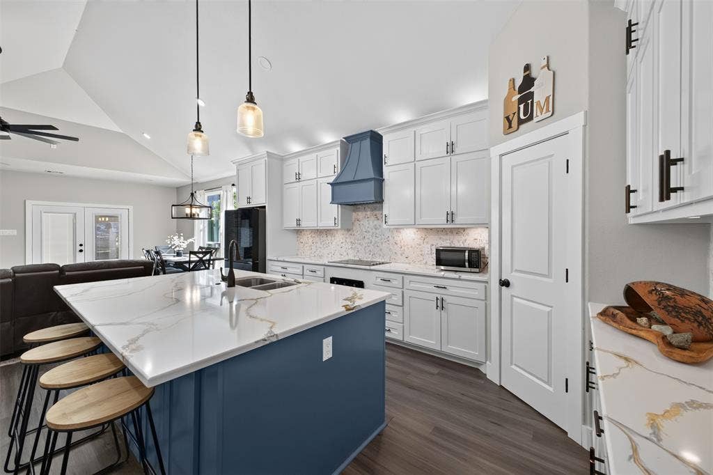 9116 Beckleycrest Avenue, Dallas, TX 75232 Beautifully designed kitchen featuring an oversized island with quartz countertops, custom cabinetry with plenty of storage, stainless steel appliances. Open to living and dining area.