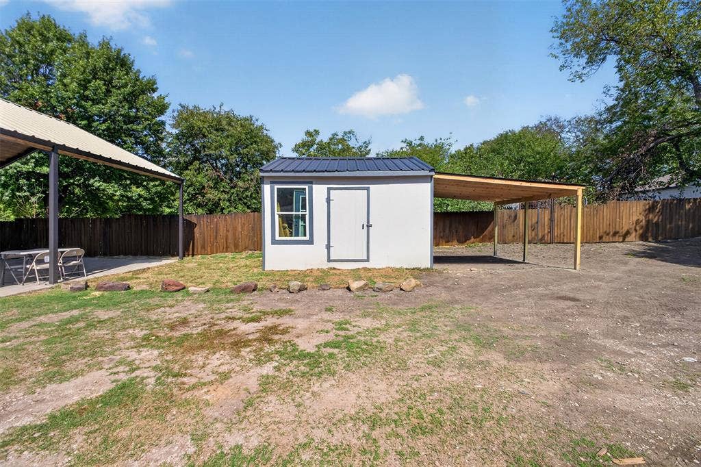 9116 Beckleycrest Avenue, Dallas, TX 75232 Detached storage building featuring a metal roof and adjoining covered area offering additional space for outdoor storage and equipment.