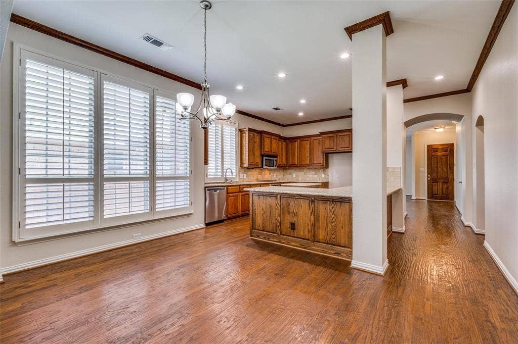 1441 Kirkwood Lane, Prosper, TX 75078 Wood-finish flooring, plantation shutters, crown molding, wood cabinetry, and a multi-light chandelier