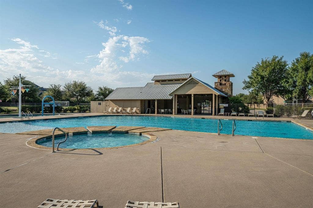 1441 Kirkwood Lane, Prosper, TX 75078 Swimming pool complex featuring a splash pad, circular spa, expansive concrete decking, and a covered clubhouse pavilion with stone accents
