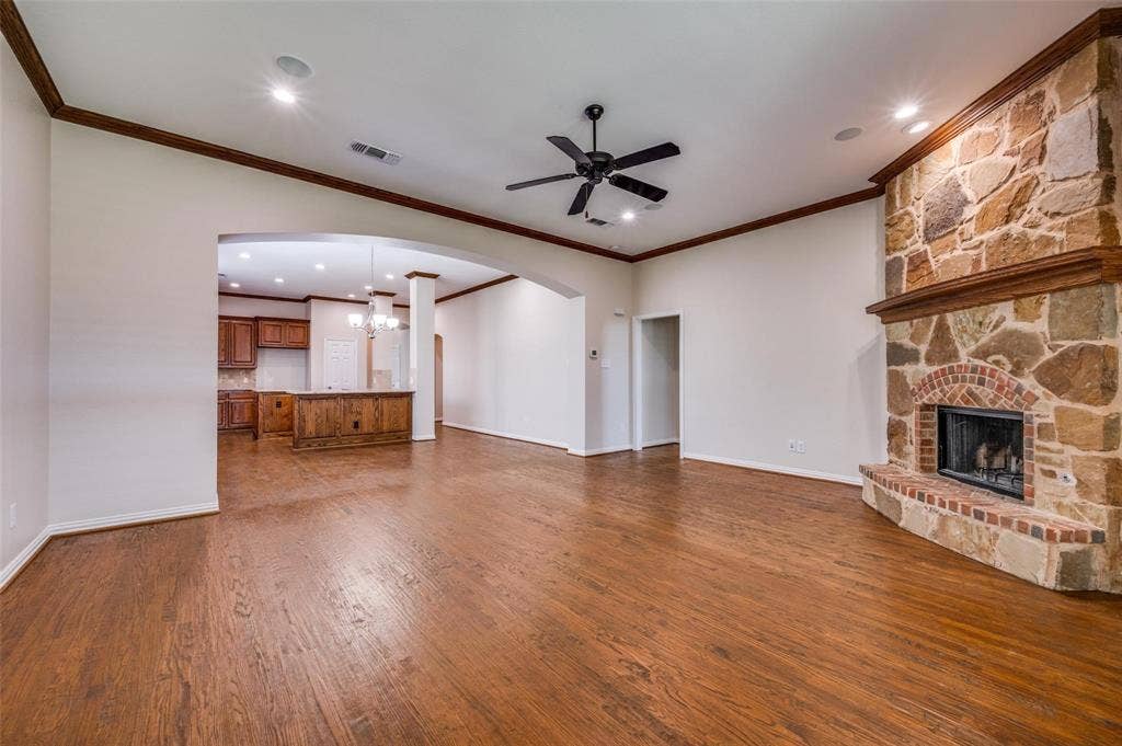 1441 Kirkwood Lane, Prosper, TX 75078 Living area featuring wood-finish flooring, crown molding, and a floor-to-ceiling stone fireplace with a brick surround