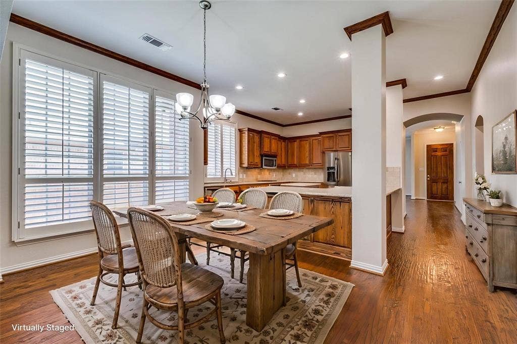 1441 Kirkwood Lane, Prosper, TX 75078 Dining area featuring wood-finish flooring, plantation shutters, crown molding, and a chandelier, complemented by recessed lighting