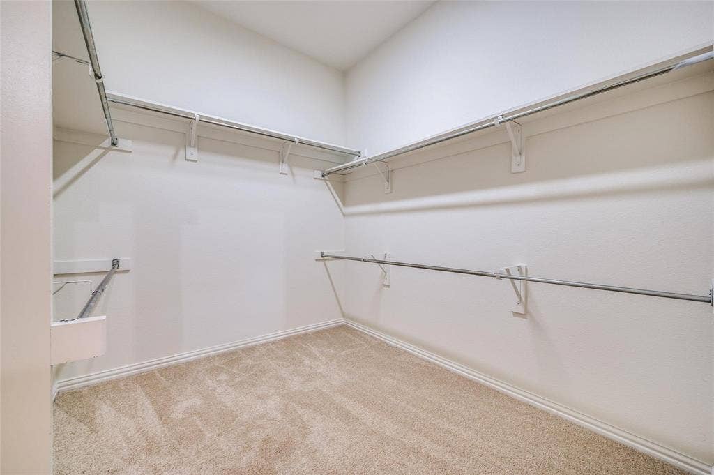 1441 Kirkwood Lane, Prosper, TX 75078 Walk-in closet featuring wall-to-wall carpeting, multiple tiers of metal clothing rods, and white wall shelving
