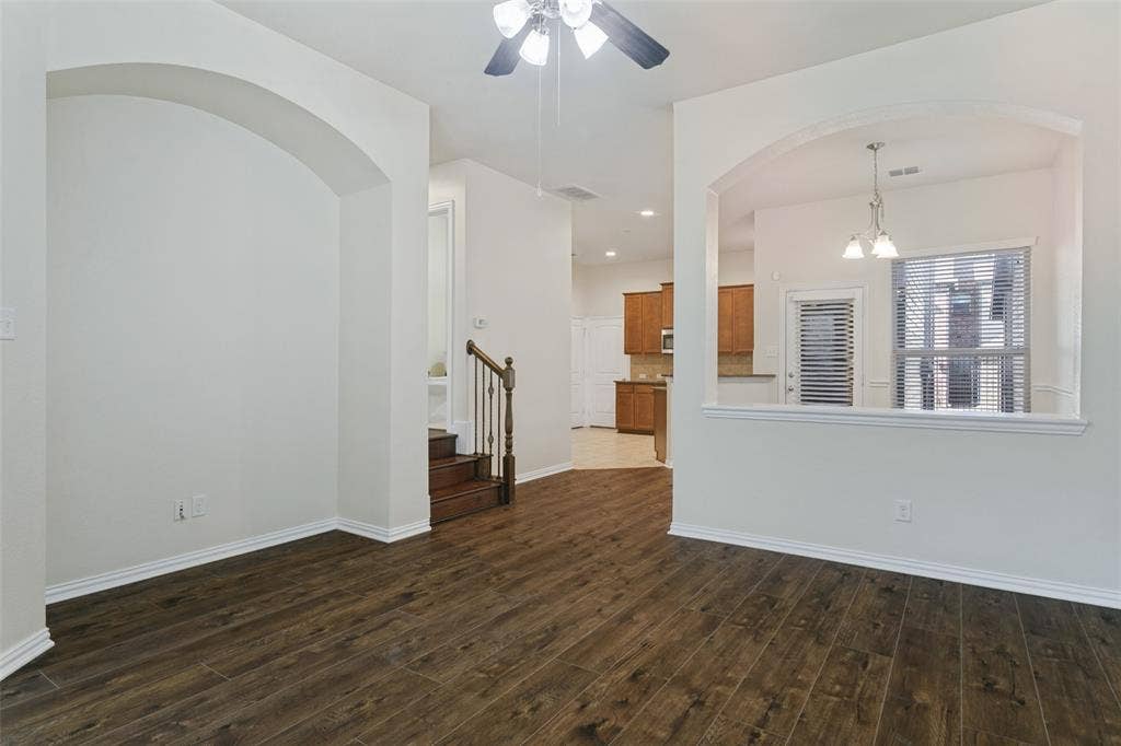 Interior space featuring wood-finish flooring, architectural arched openings, recessed lighting, a ceiling fan with integrated light fixture, and a staircase with a wooden handrail and metal balusters