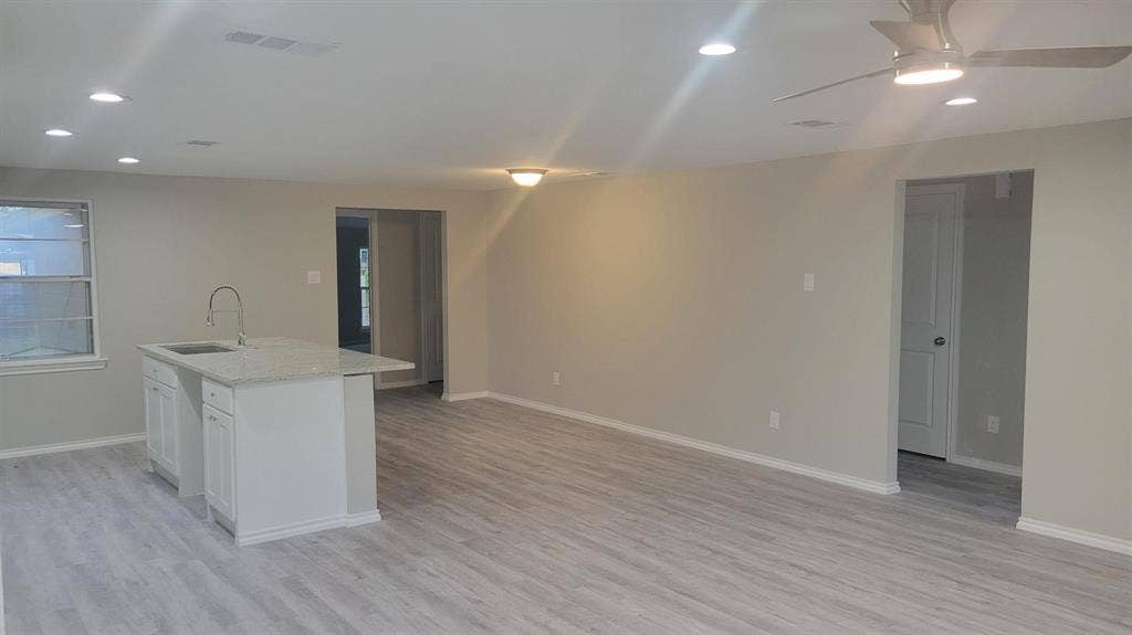 707 Korgan Street, Dallas, TX 75216 Open-concept living space featuring wood-finish flooring, recessed lighting, a ceiling fan, and a kitchen island with a stone-surface countertop and integrated stainless steel sink