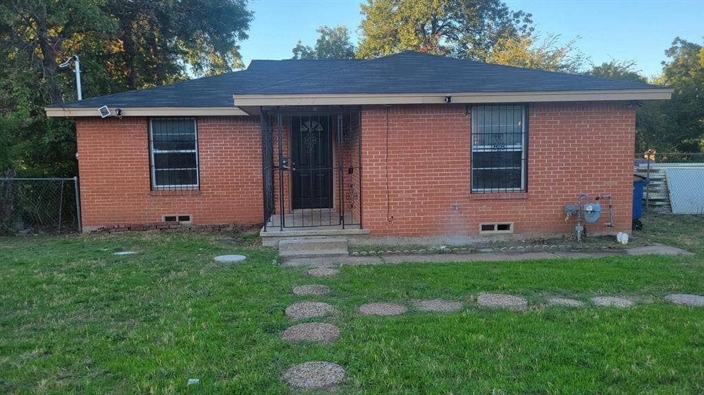 707 Korgan Street, Dallas, TX 75216 Single-story residence featuring red brick exterior, low-pitch roof, metal security entry door, and stone paver walkway