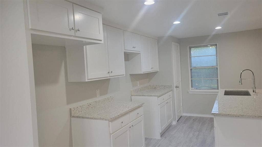 707 Korgan Street, Dallas, TX 75216 Kitchen featuring white cabinetry, speckled stone-finish countertops, wood-finish flooring, recessed lighting, and a high-arch pull-down faucet
