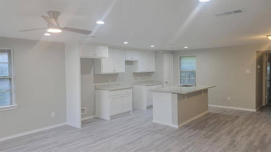 707 Korgan Street, Dallas, TX 75216 Kitchen featuring white cabinetry, stone-finish countertops, an island with an undermount sink, recessed lighting, and wood-finish flooring