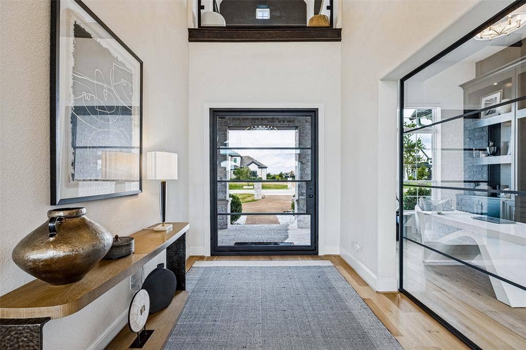 4604 Devon Drive, Parker, TX 75002 Entryway featuring a double-height ceiling, large-format iron and glass front door, wood-finish flooring, and a floor-to-ceiling glass-paneled partition