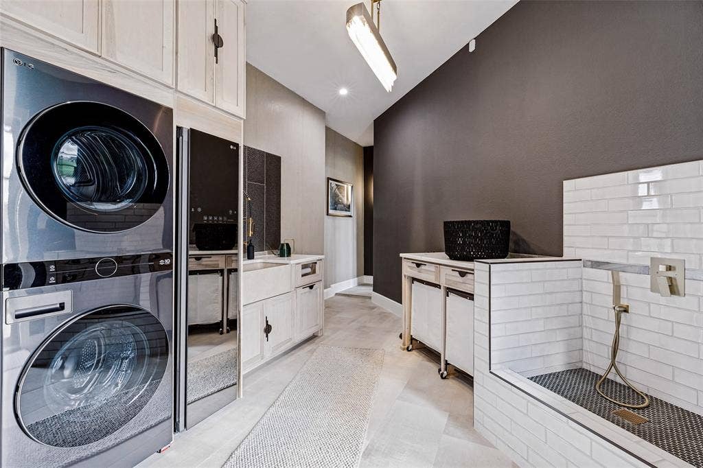 4604 Devon Drive, Parker, TX 75002 Laundry space featuring custom light-toned cabinetry, farmhouse-style sink, built-in pet wash station with subway tile surround, and stacked appliance configuration