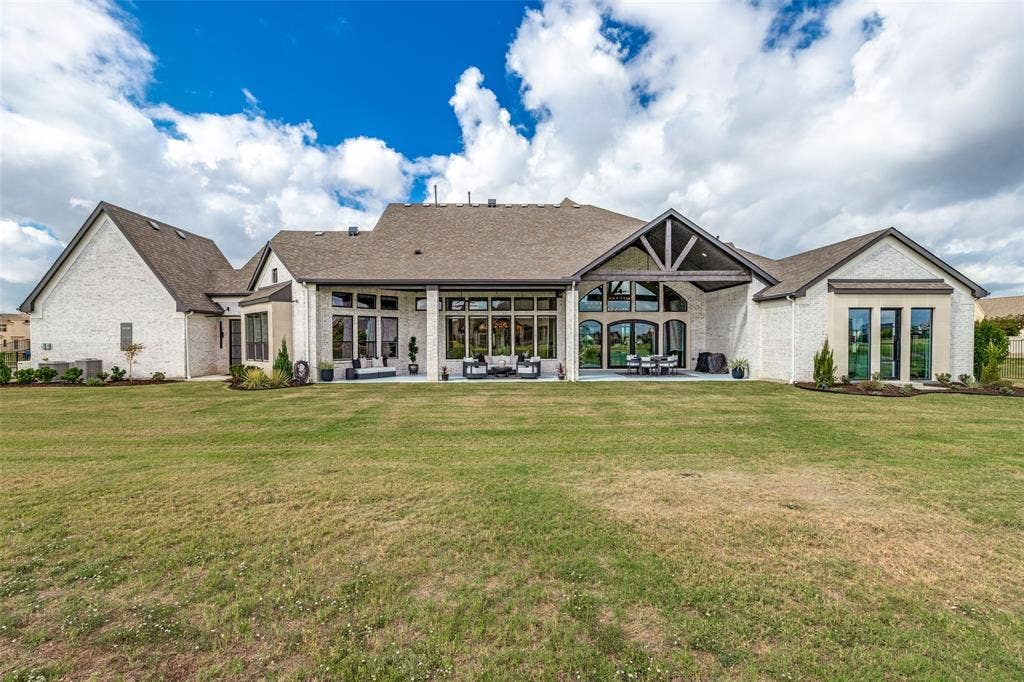 4604 Devon Drive, Parker, TX 75002 Rear exterior featuring a brick facade, covered patio with vaulted timber-truss ceiling, multi-pane floor-to-ceiling windows, and expansive grass lawn