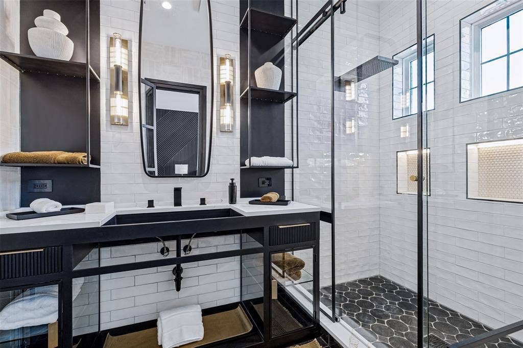 4604 Devon Drive, Parker, TX 75002 Custom metal-framed vanity with integrated shelving, quartz countertop, rectangular basin, wall-mounted vertical light fixtures, and glass-enclosed shower with tiled niches