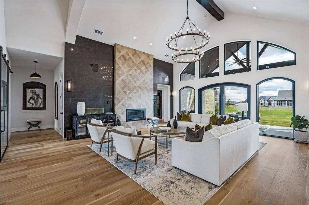 4604 Devon Drive, Parker, TX 75002 Vaulted ceilings with exposed beams, wood-finish flooring, floor-to-ceiling multi-tone stone fireplace, arched windows, and dual-tier wagon wheel chandelier