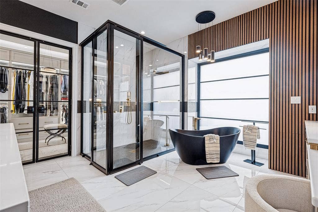 4604 Devon Drive, Parker, TX 75002 Enclosed glass shower with black metal framing, matte black freestanding soaking tub, vertical wood-slat accent wall, and large-format tile flooring