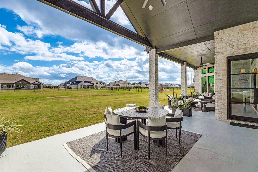 4604 Devon Drive, Parker, TX 75002 Covered rear patio featuring a vaulted ceiling with exposed timber beams, brick column supports, concrete flooring, and multi-pane black-trimmed glass doors