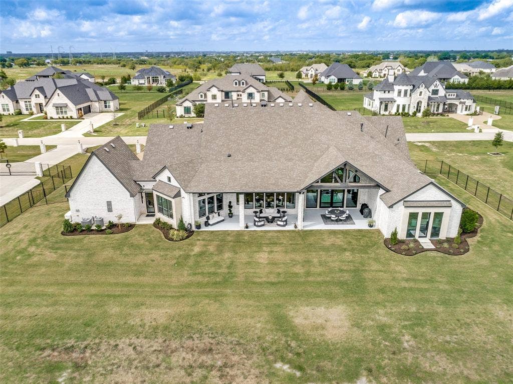 4604 Devon Drive, Parker, TX 75002 Aerial perspective of a multi-gabled residence featuring a light-colored brick exterior, expansive rear covered patio, large windows, and an encompassing fence