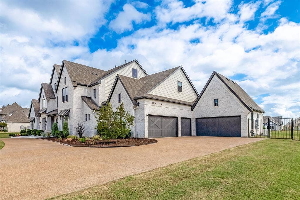 4604 Devon Drive, Parker, TX 75002 Multi-gabled exterior featuring light-toned brick masonry, horizontal siding accents, a five-car garage with dark carriage-style doors, and an expansive stamped concrete driveway