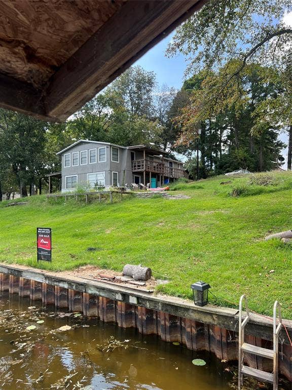 3723 County Road 4806, Athens, TX 75752 Two-story residence featuring wood siding, an elevated wood deck, a bulkhead shoreline, and a built-in metal ladder providing water access