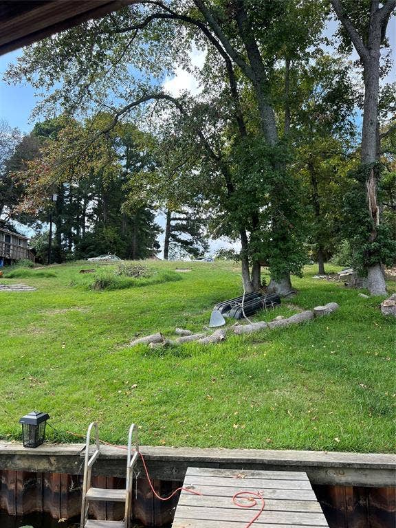 3723 County Road 4806, Athens, TX 75752 Waterfront lot featuring a wooden pier with integrated ladder and bulkhead, mature tree canopy, and expansive grass lawn
