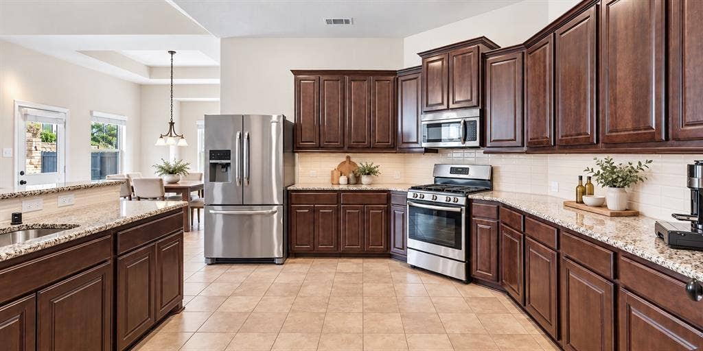 632 Grisham Drive, Fate, TX 75087 Kitchen featuring stained wood cabinetry, stone countertops, tiled backsplash, stainless steel appliances, and ceramic tile flooring