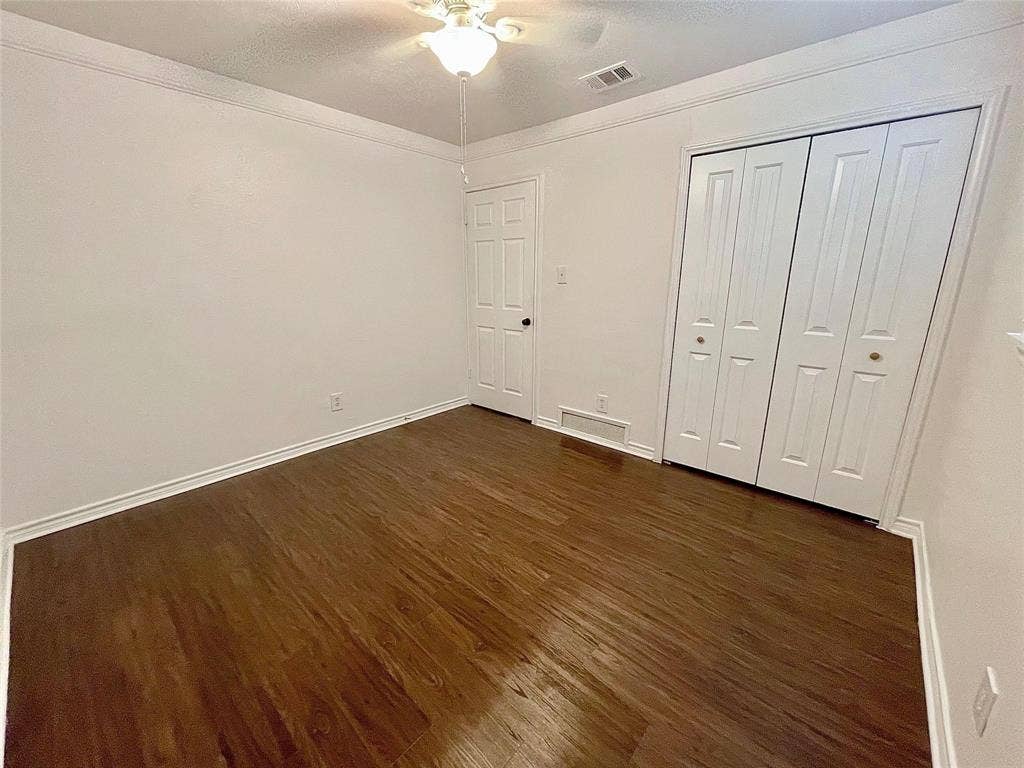 Wood-finish flooring, crown molding, multi-panel doors, bi-fold closet doors, and a ceiling fan with integrated lighting