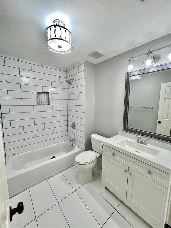 White subway-tile tub surround with decorative recessed shelving, white shaker-style vanity with integrated rectangular sink, large-format tile flooring, and decorative drum-style ceiling lighting