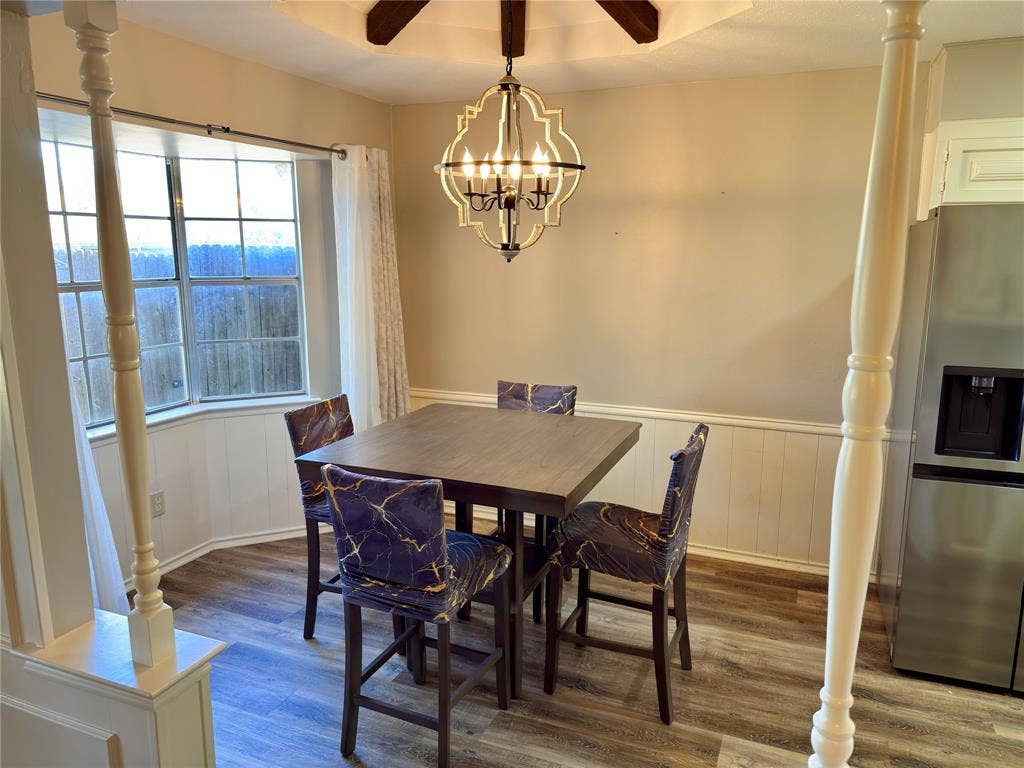 Bay window featuring multi-pane glass, wood-finish flooring, wainscoting, and a geometric metal pendant light fixture