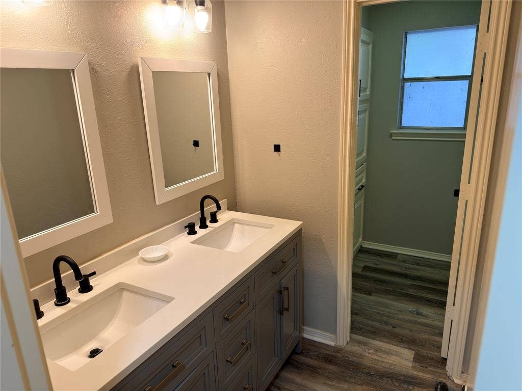 Dual-sink vanity with a solid-surface countertop, undermount basins, matte black widespread faucets, and framed wall mirrors