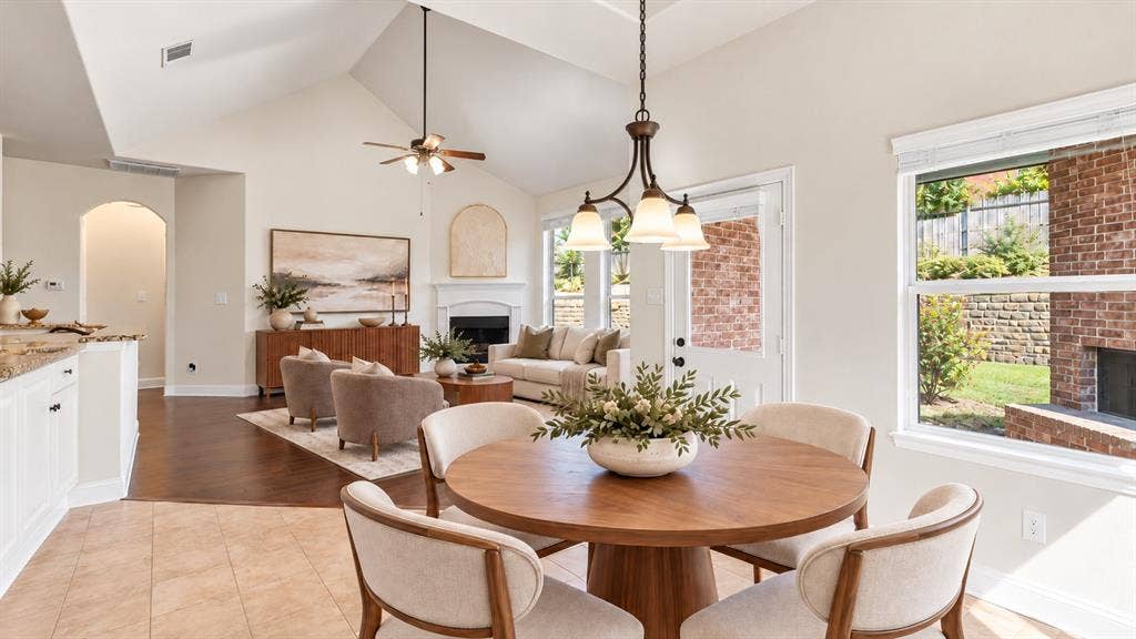 632 Grisham Drive, Fate, TX 75087 Vaulted ceilings featuring a chandelier and ceiling fan, wood-finish flooring, a fireplace with a white mantel, and a multi-pane glass door