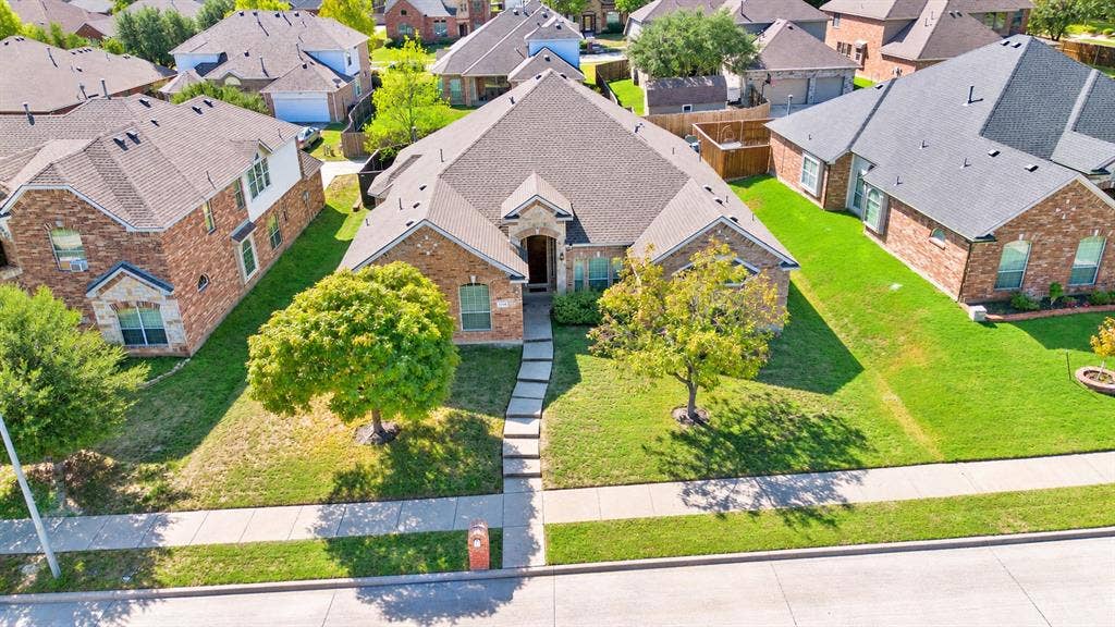1736 Blue Stream Drive, DeSoto, TX 75115 Single-story brick exterior featuring a multi-gabled roofline, stone accents, concrete walkway, and manicured front lawn