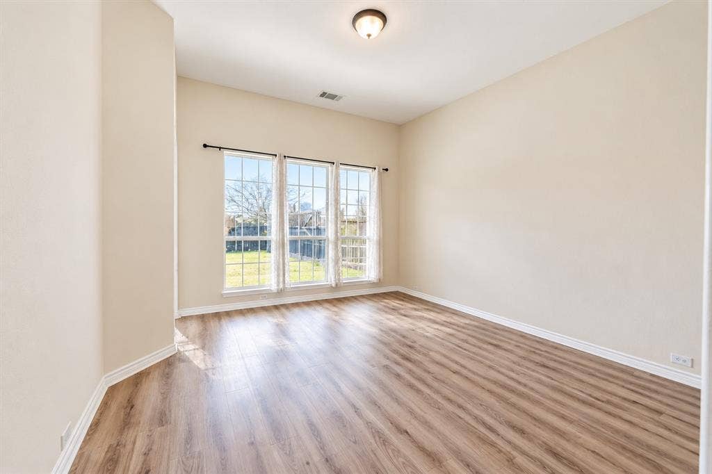 1736 Blue Stream Drive, DeSoto, TX 75115 Family room featuring wood-look LVP flooring, a triple-pane window arrangement, neutral wall paint, and a ceiling-mounted light fixture