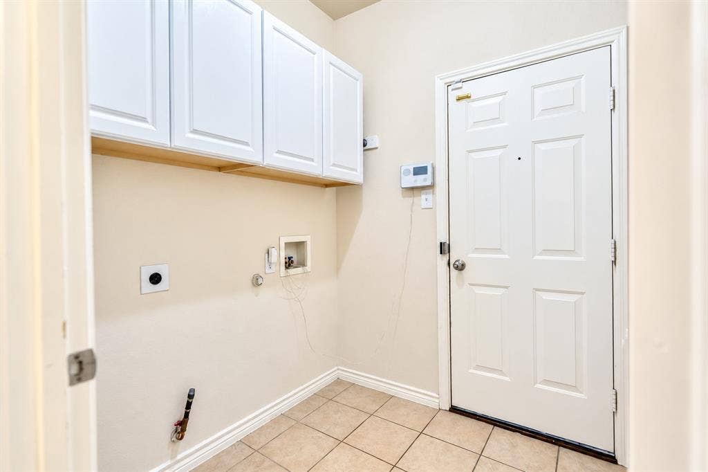 1736 Blue Stream Drive, DeSoto, TX 75115 Wall-mounted white cabinetry, tile flooring, six-panel door, and laundry utility hookups