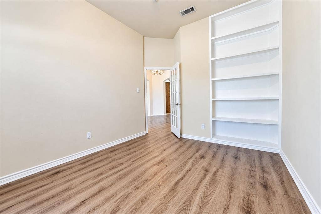 1736 Blue Stream Drive, DeSoto, TX 75115 Room featuring wood-look LVP flooring, built-in white shelving, and a glass-paneled door