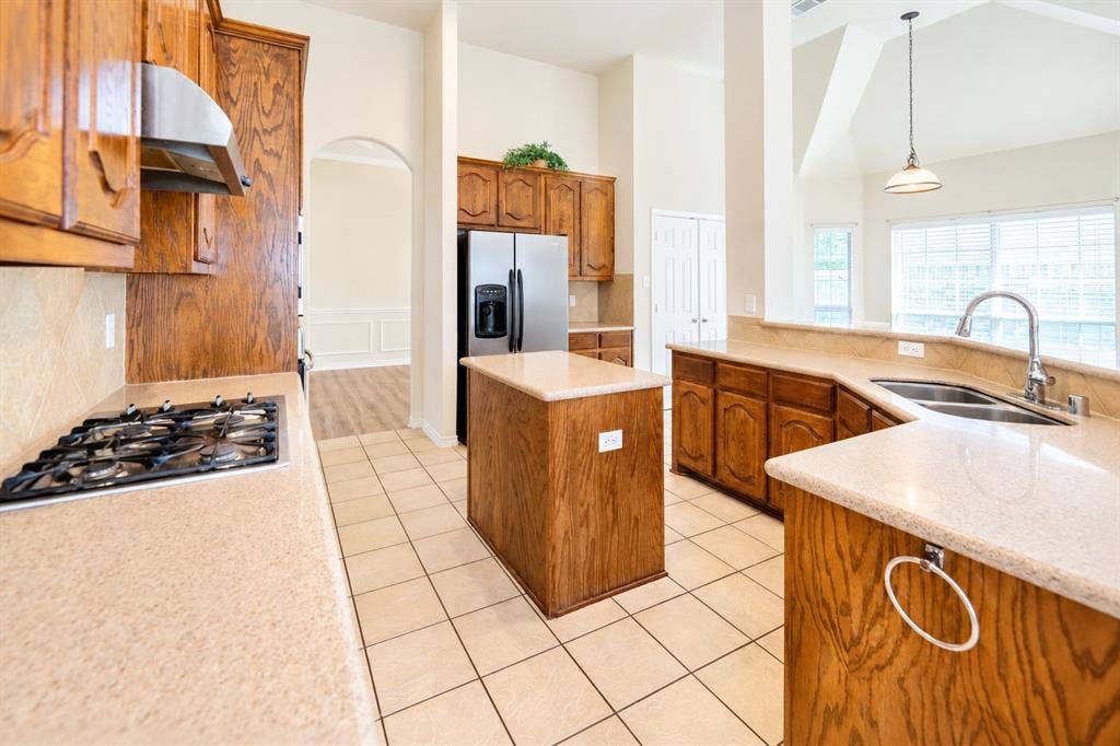 1736 Blue Stream Drive, DeSoto, TX 75115 Kitchen featuring wood cabinetry, granite countertops, stainless steel gas cooktop, center island, and tile flooring