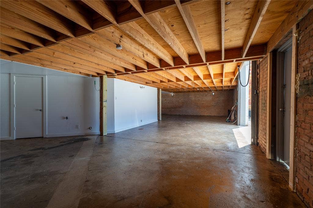 3014 Canton Street, Dallas, TX 75226 Industrial-style interior featuring exposed wooden ceiling joists, concrete flooring, exposed brick wall segments, and painted white wall finishes