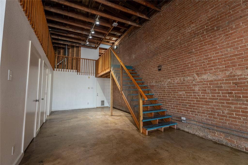 3014 Canton Street, Dallas, TX 75226 Exposed brick wall, polished concrete flooring, open-beam wood ceiling, and custom staircase featuring wood handrails and glass panels