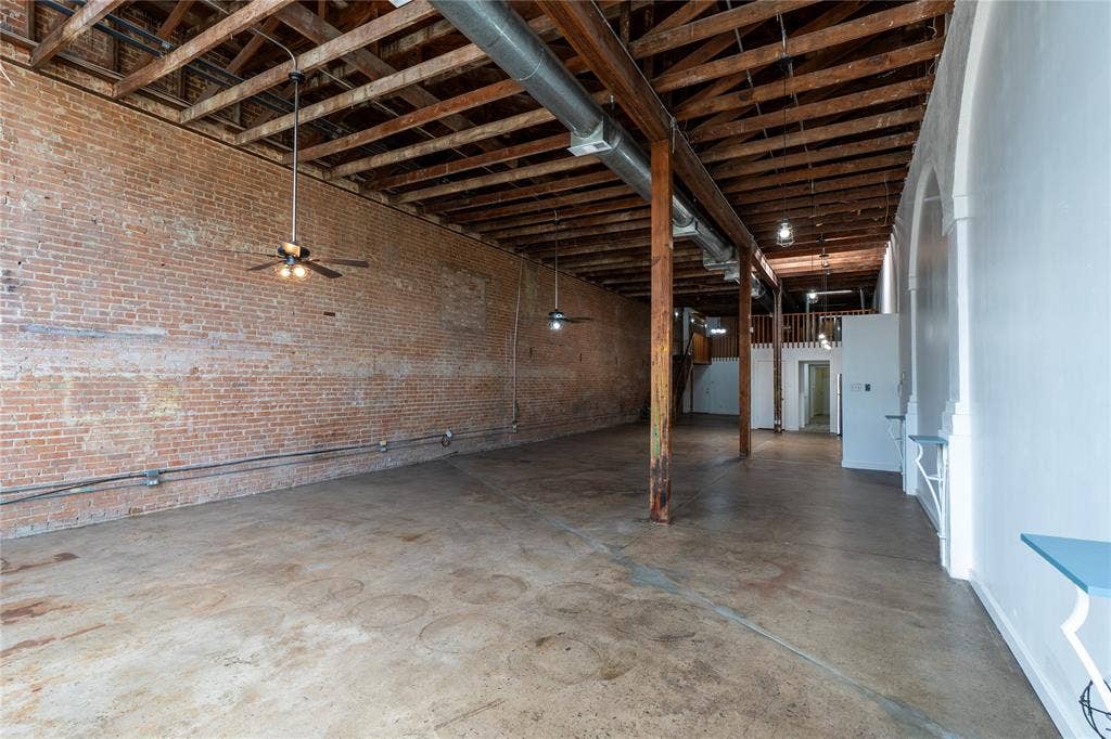 3014 Canton Street, Dallas, TX 75226 Open interior space featuring exposed brick walls, industrial timber ceiling beams, polished concrete flooring, exposed ductwork, and structural wooden support columns