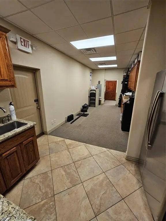 1831 W Louisiana Street, McKinney, TX 75069 Utility area featuring wood-finish cabinetry, stone-style countertop with integrated sink, drop-ceiling grid with recessed lighting, and mixed tile and carpeting