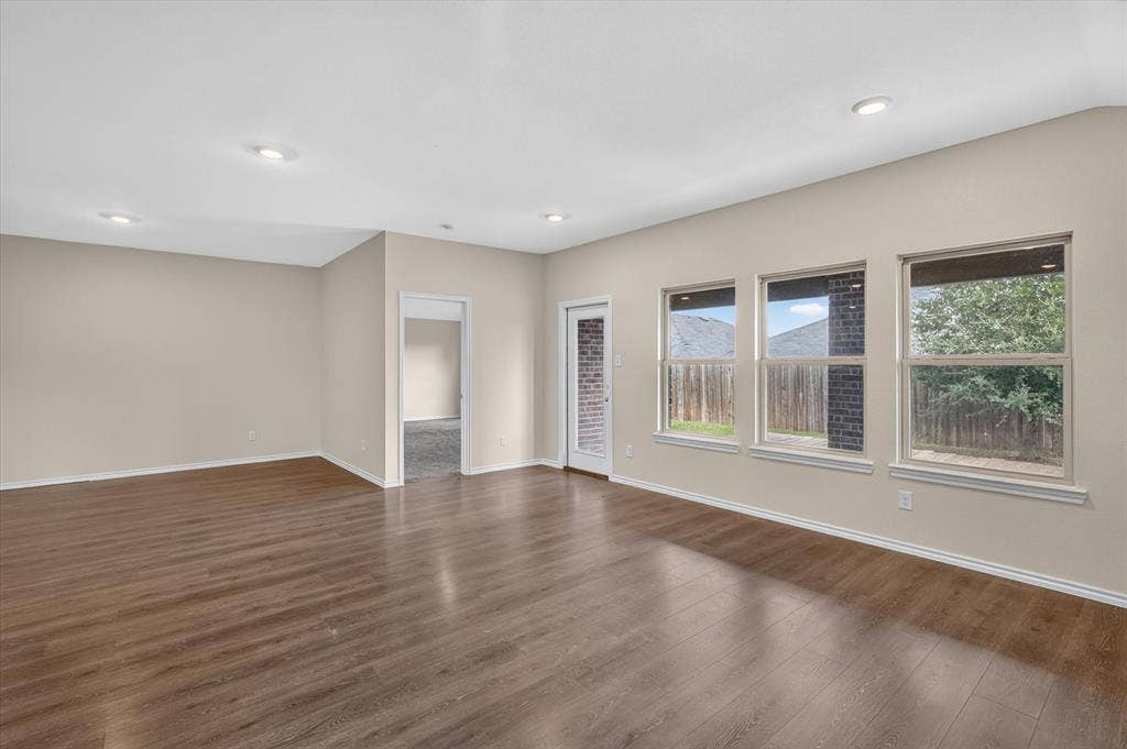 114 Real Quiet Lane, Caddo Mills, TX 75135 Open-concept interior featuring wood-finish flooring, neutral wall paint, recessed lighting, and a series of windows