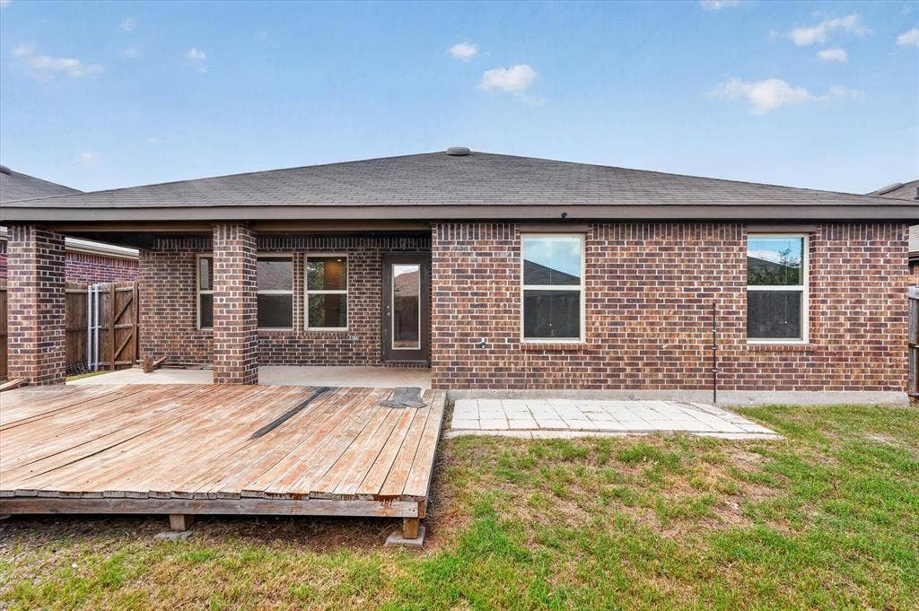 114 Real Quiet Lane, Caddo Mills, TX 75135 Brick exterior featuring a covered patio, wood deck, concrete paver area, and hip roofline
