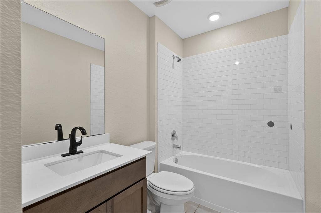 114 Real Quiet Lane, Caddo Mills, TX 75135 Bathroom featuring a vanity with white countertop, integrated rectangular sink, and matte black faucet, paired with a subway-tiled shower surround